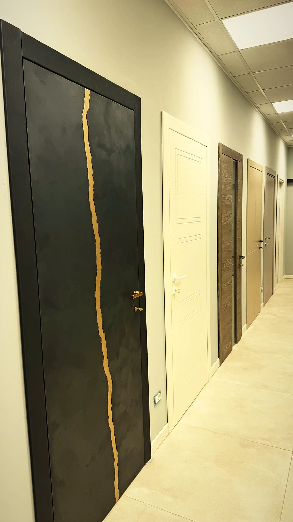 Corridoio delle porte nello showroom Mood Abitare, con una porta scura dalla venatura dorata in primo piano
